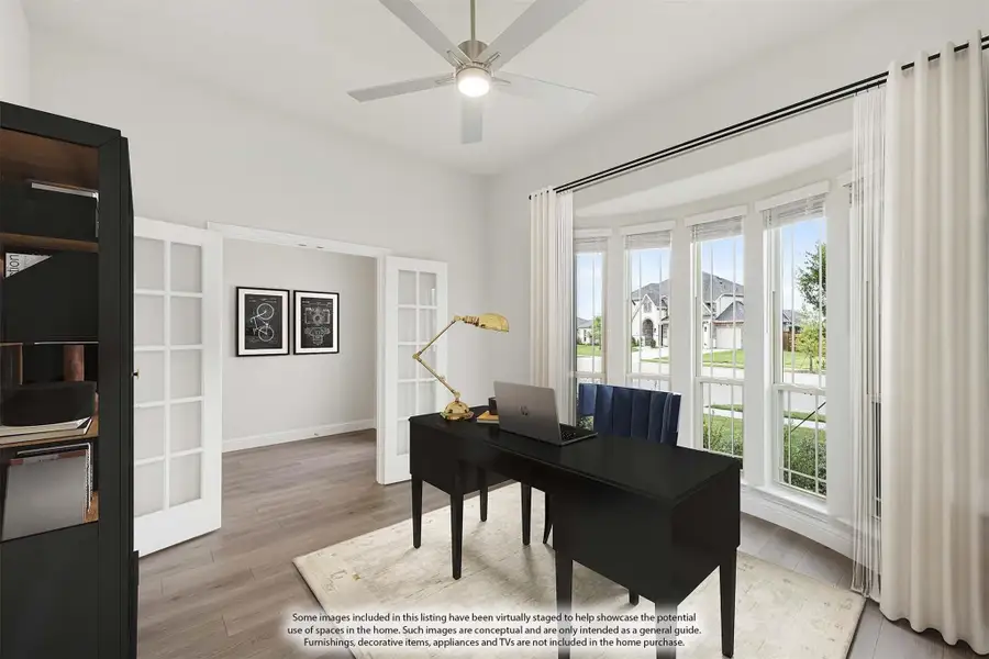 Home office with black desk, hardwood floors, ceiling fan, and large windows with neighborhood view Home office with black desk, hardwood floors, ceiling fan, and large windows with neighborhood view
