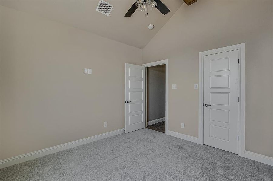 Unfurnished bedroom featuring high vaulted ceiling, ceiling fan, beamed ceiling, and light carpet