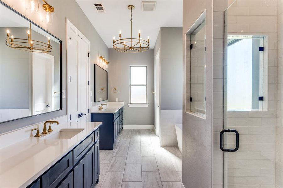 Bathroom featuring a chandelier, two vanities, a stall shower, and a tub to relax in Bathroom featuring a chandelier, two vanities, a stall shower, and a tub to relax in