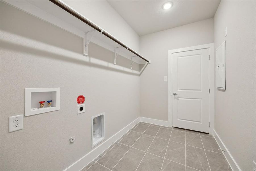 Laundry area with hookup for a gas dryer, light tile patterned flooring, electric dryer hookup, and washer hookup