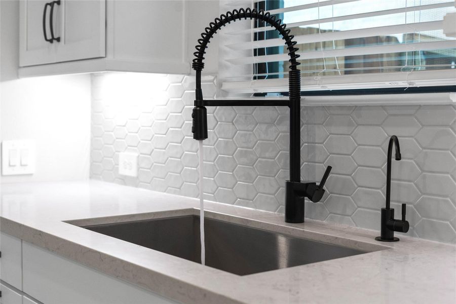Positioned below a large window is the under-mount sink, upgraded matte black commercial-style spring pull-down faucet and a matching dedicated drinking water dispenser. Positioned below a large window is the under-mount sink, upgraded matte black commercial-style spring pull-down faucet and a matching dedicated drinking water dispenser.