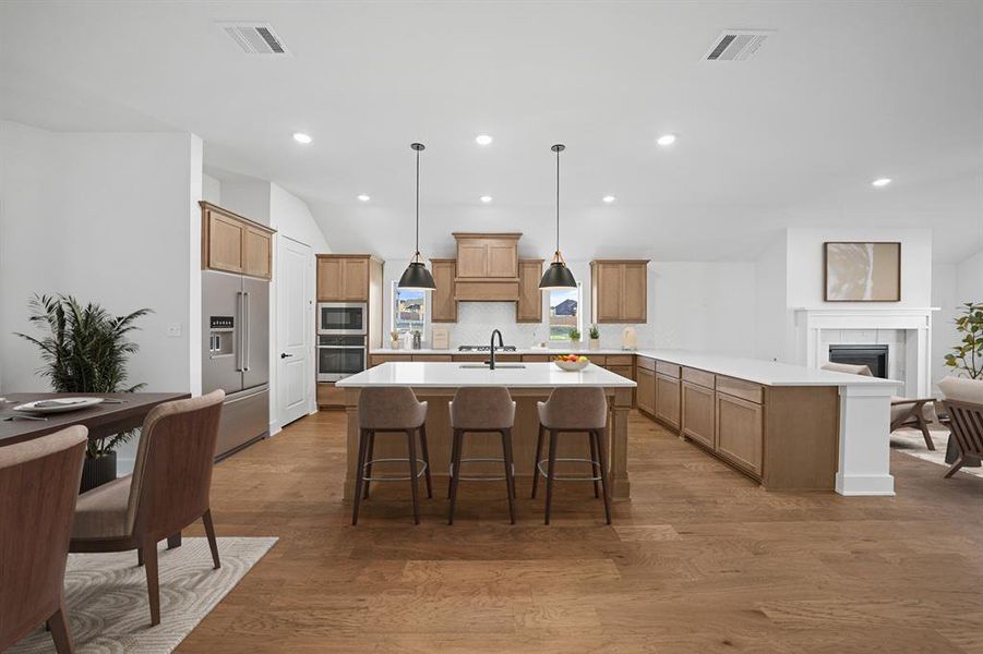 Kitchen with a peninsula, a breakfast bar, dark wood-style floors, decorative backsplash, and appliances with stainless steel finishes Kitchen with a peninsula, a breakfast bar, dark wood-style floors, decorative backsplash, and appliances with stainless steel finishes