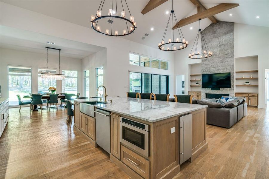 Kitchen with beamed ceiling, light hardwood / wood-style floors, a large island, and high vaulted ceiling