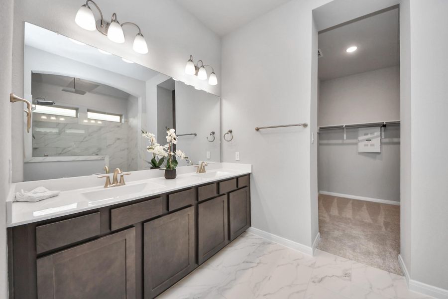 Primary bathroom with marble vanity tops and oversized built in sinks facing the primary closet.