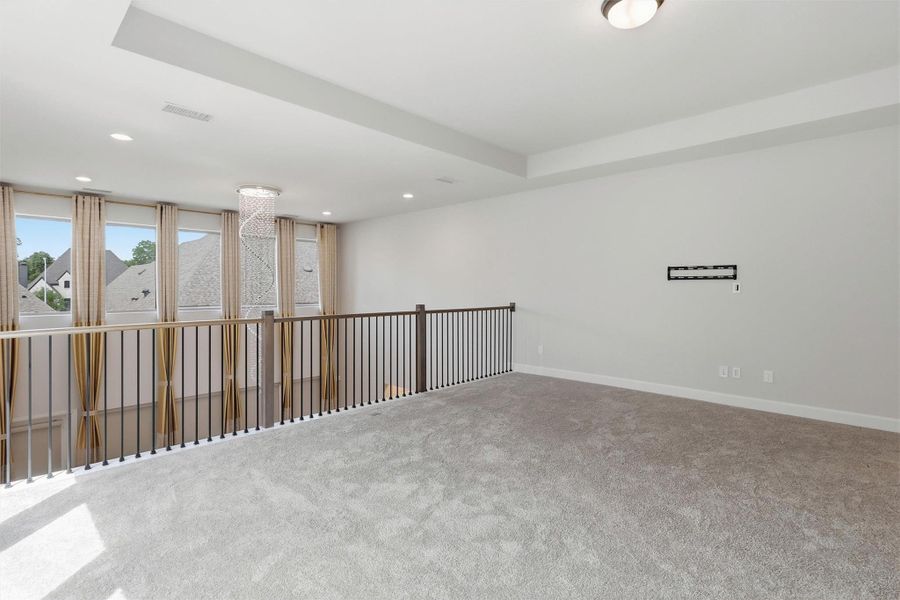 Another view showcases the generous proportions of this oversized game room. The open railing overlooks the impressive two-story foyer while walls of windows and elegant finishes make the space feel bright, open, and inviting.