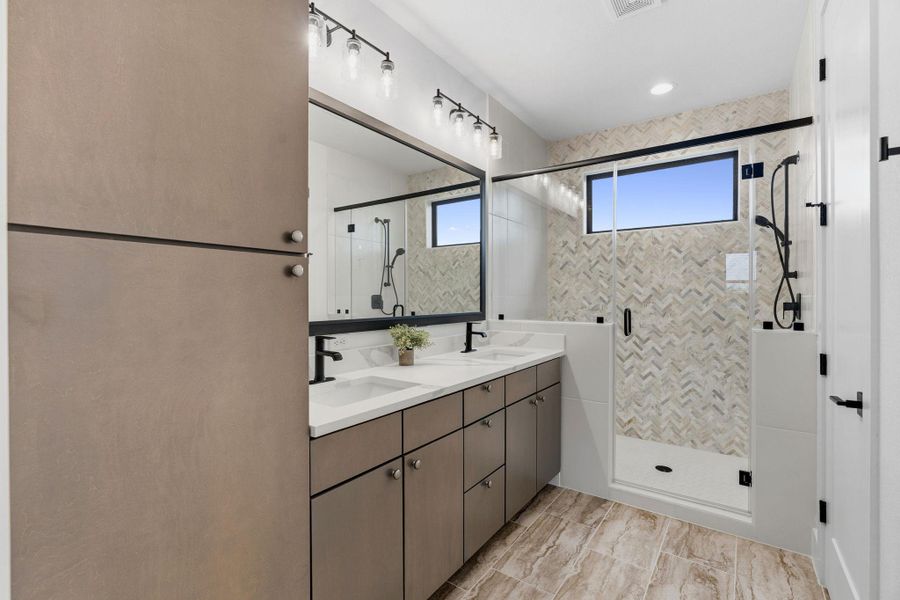 Bright, well-designed bath featuring a spacious walk-in shower, contemporary fixtures, dual sinks, and ample storage.