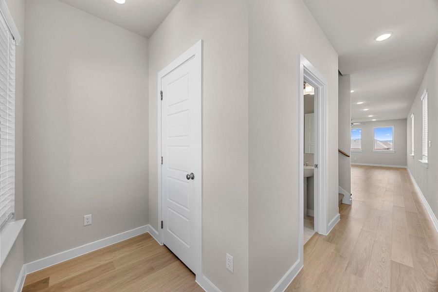 A well-lit hallway with natural wood flooring leads toward a bright living area, offering a sense of openness. A well-lit hallway with natural wood flooring leads toward a bright living area, offering a sense of openness.