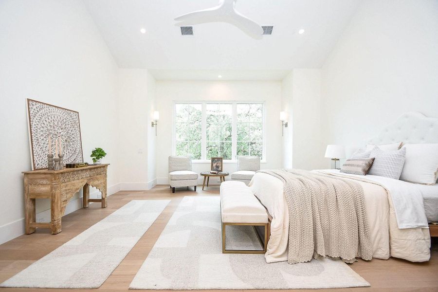 Bright, spacious bedroom with a large window offering natural light. Features a cozy bed with neutral bedding, a decorative wooden console, and minimalistic decor for a serene atmosphere.