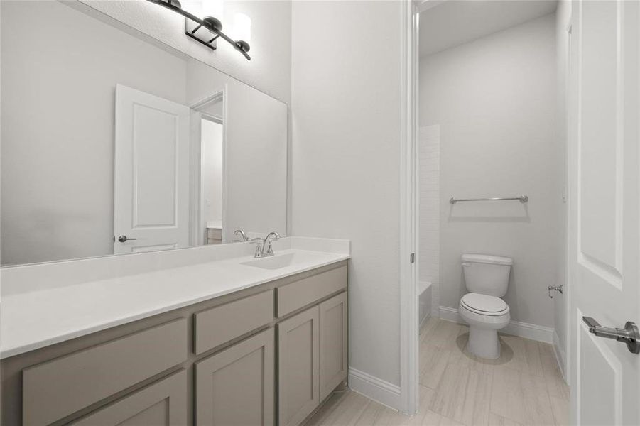 Bathroom featuring a washtub, vanity, and toilet