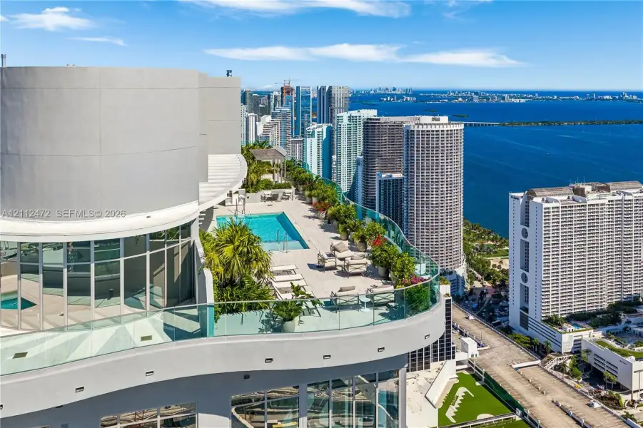 Expansive terrace featuring a rectangular swimming pool, glass paneled perimeter railing, large-format tile flooring, and integrated landscaping