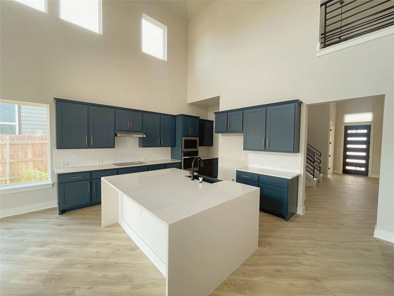 An open concept kitchen features sleek cabinetry and a generously sized island, connecting to a bright living area. An open concept kitchen features sleek cabinetry and a generously sized island, connecting to a bright living area.