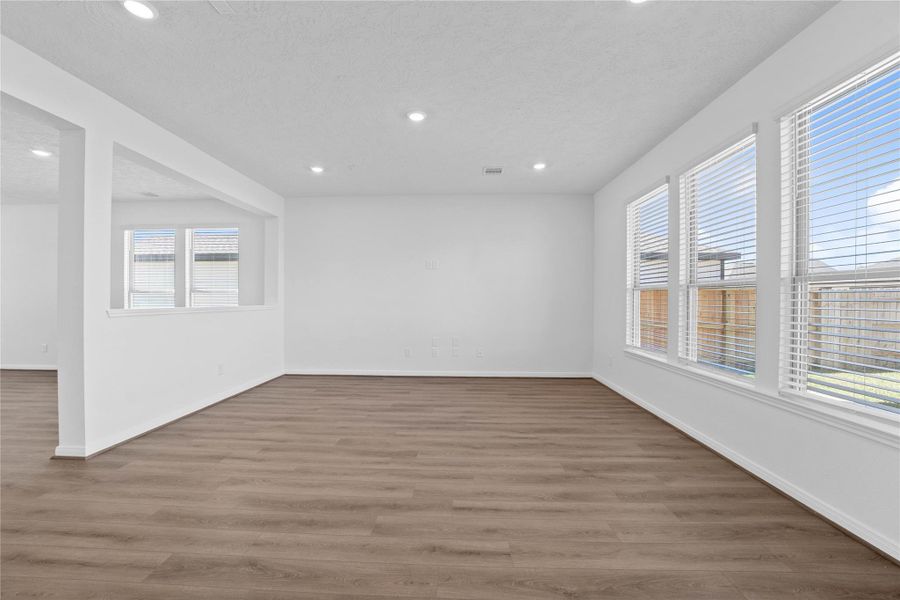 Bring family and friends together in this beautiful family room! It features high ceilings, recessed lighting, custom paint, stunning flooring, and large windows that fill the space with natural light all day long.