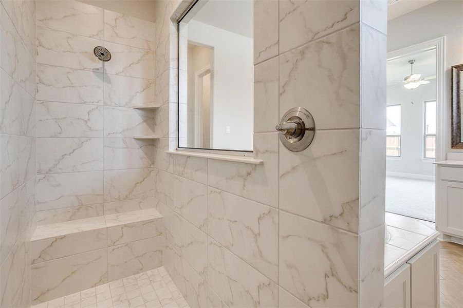 Bathroom featuring tiled shower and ceiling fan