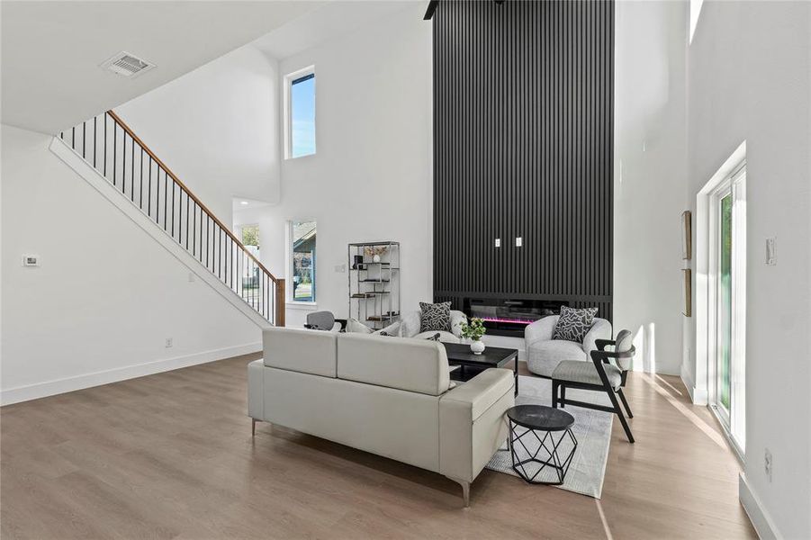 Living room with light wood-type flooring and a towering ceiling