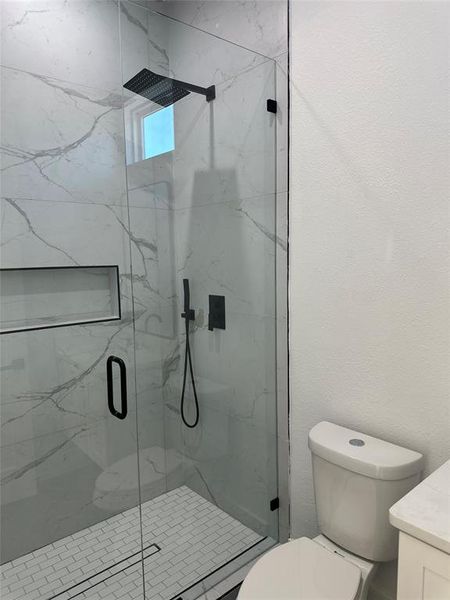 Bathroom with vanity, a shower with shower door, and toilet