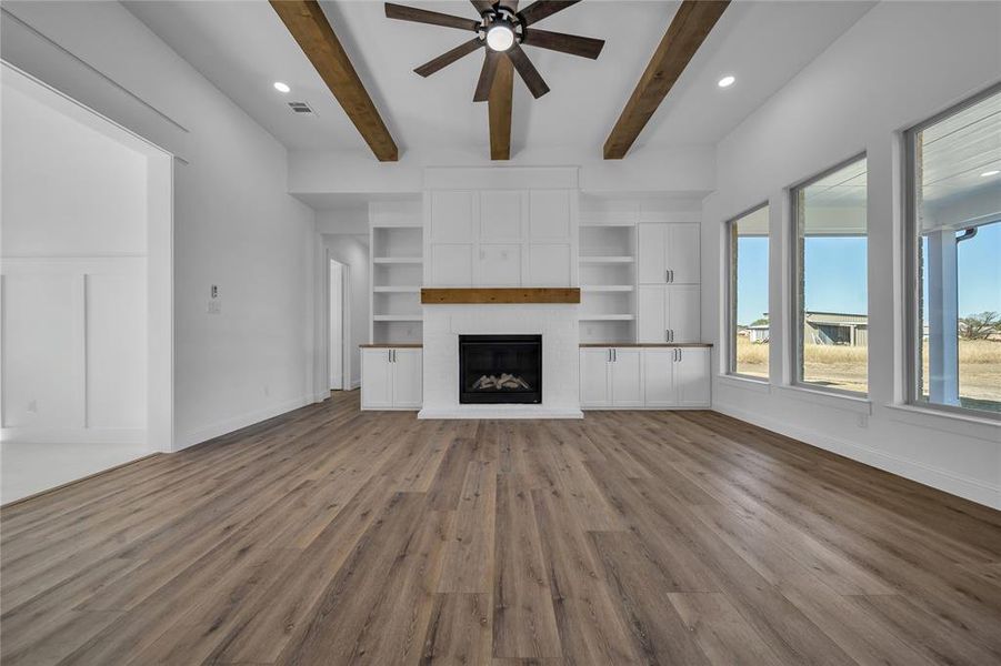 Unfurnished living room featuring a fireplace, wood finished floors, recessed lighting, a ceiling fan, and beamed ceiling