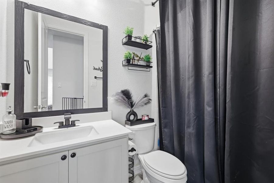 Bathroom featuring a shower with shower curtain, vanity, and a textured wall