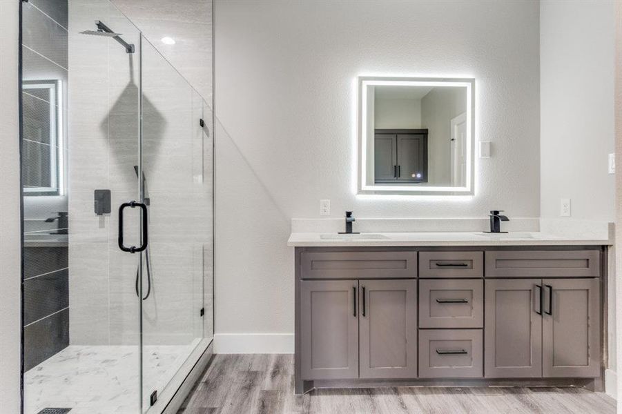 Bathroom featuring a shower with door, vanity, and hardwood / wood-style flooring