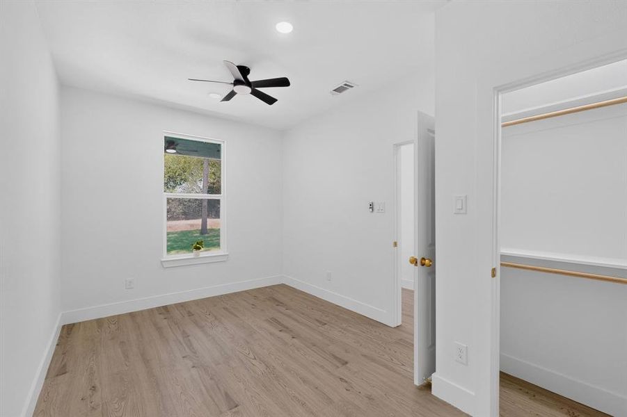 Room featuring wood-finish flooring, a ceiling fan with integrated lighting, recessed overhead lighting, and a window with exterior tree scenery