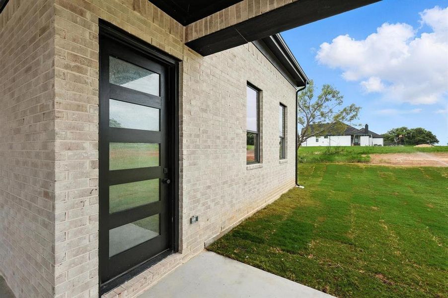 Property entrance with a yard and brick siding