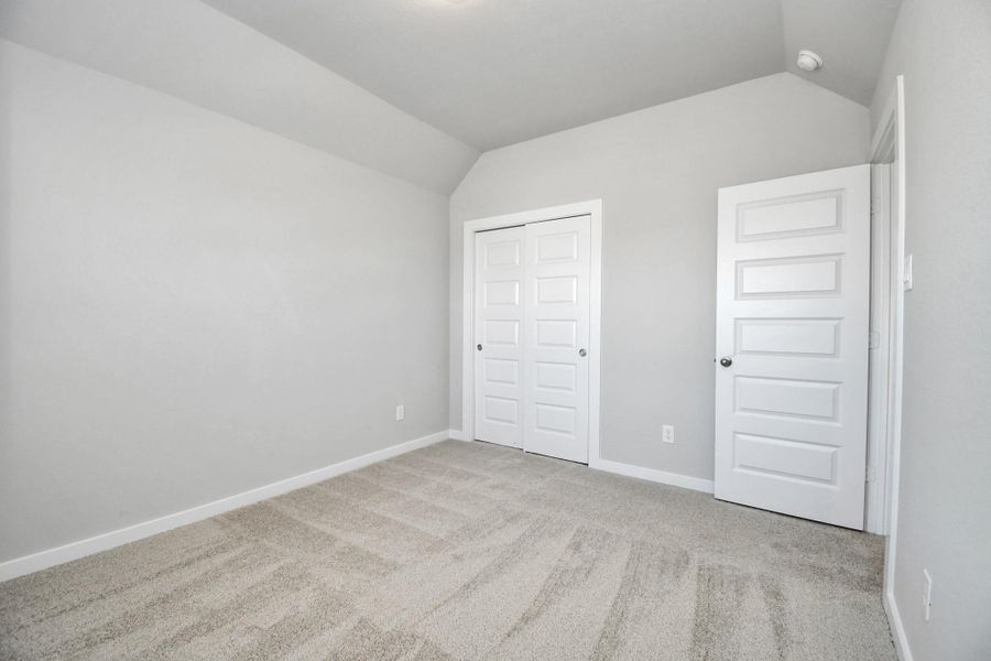 Secondary bedroom features plush carpeting, large windows that let in plenty of natural light, bright paint, and spacious closets. Sample photo of completed home with similar floor plan. Actual colors and selections may vary.