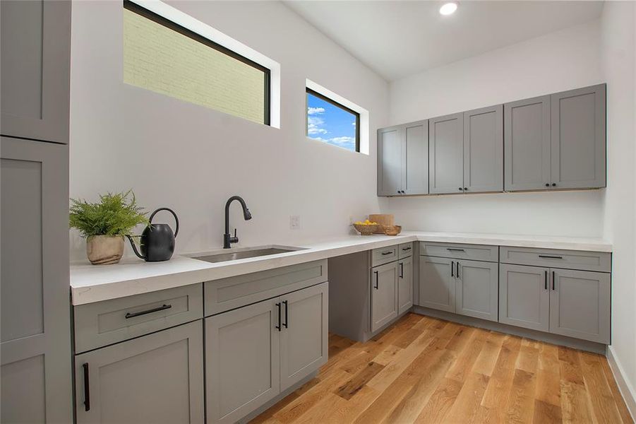 Kitchen with gray cabinets, light hardwood / wood-style flooring, and sink