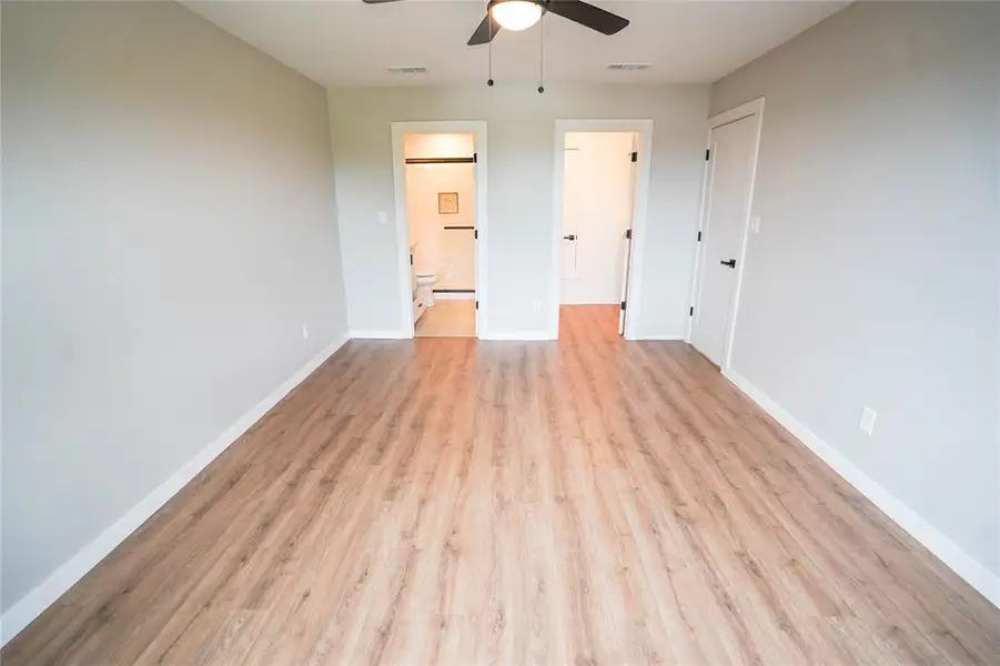 Unfurnished bedroom featuring light wood-style flooring, connected bathroom, and a ceiling fan