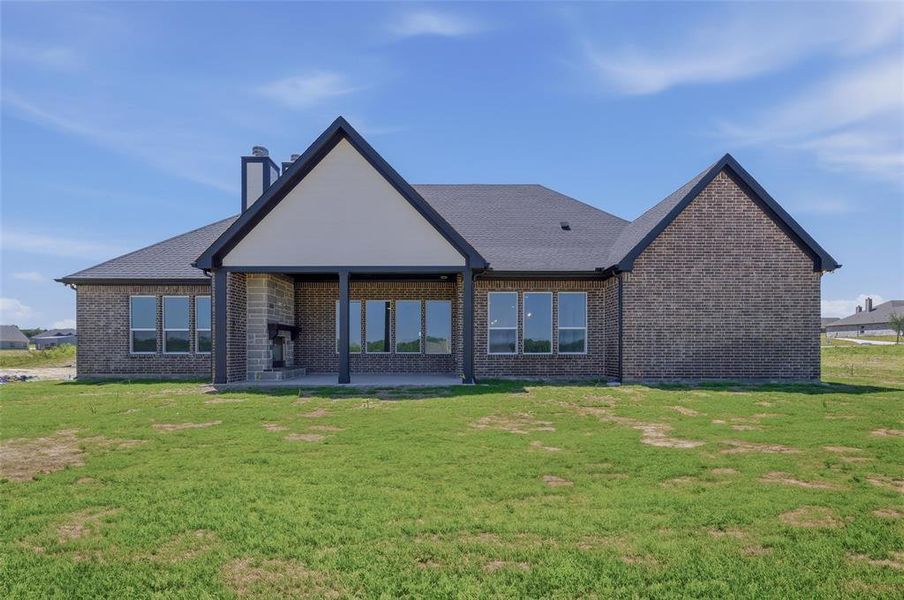 Expansive rear exterior featuring a covered patio with an outdoor fireplace