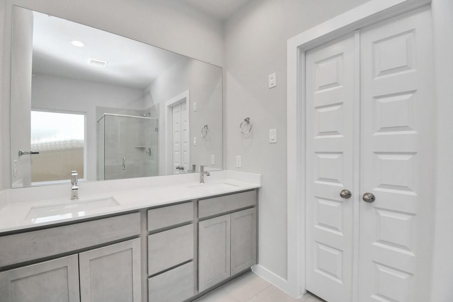 Elevate your daily routine at the elegant vanity, now equipped with double sinks, light countertops, modern hardware, and beautiful recessed lights.