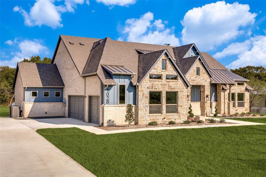 View of front facade featuring a standing seam roof, a front yard, concrete driveway, a metal roof, and stone siding View of front facade featuring a standing seam roof, a front yard, concrete driveway, a metal roof, and stone siding