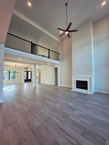 Two story family room with large wide catwalk looking below, and beautiful gas fireplace.