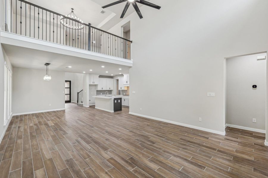 Unfurnished living room with a high ceiling, a ceiling fan, baseboards, a chandelier, and recessed lighting Unfurnished living room with a high ceiling, a ceiling fan, baseboards, a chandelier, and recessed lighting