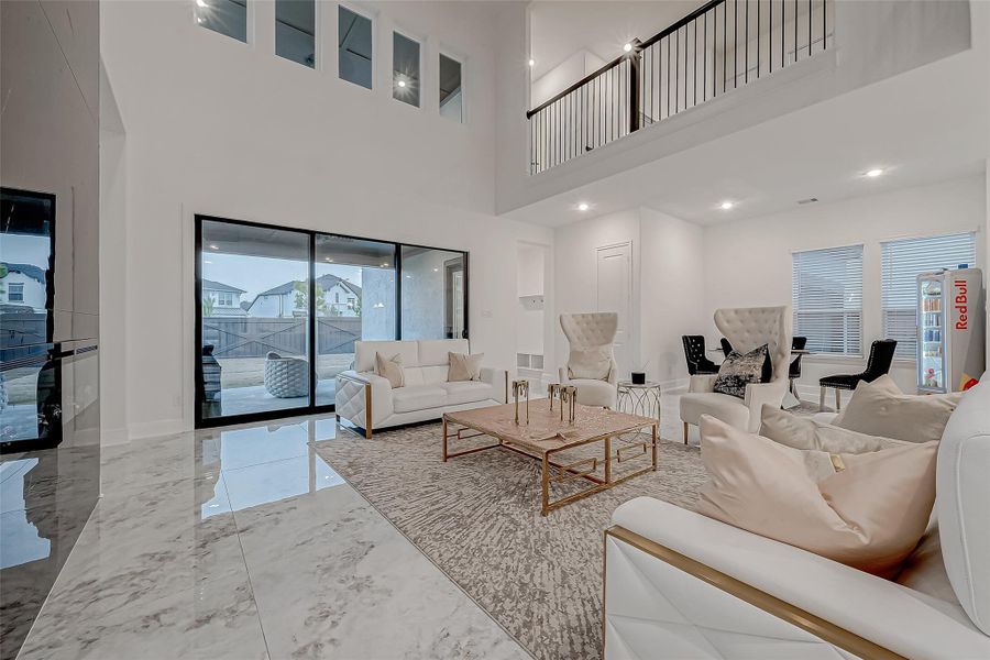 Family Room: Designed for comfort and style, the floor-to-ceiling tiled electric fireplace complements a wall of windows with patio sliding doors, seamlessly connecting indoor and outdoor spaces. Upstairs balcony overlooks foyer and family room.