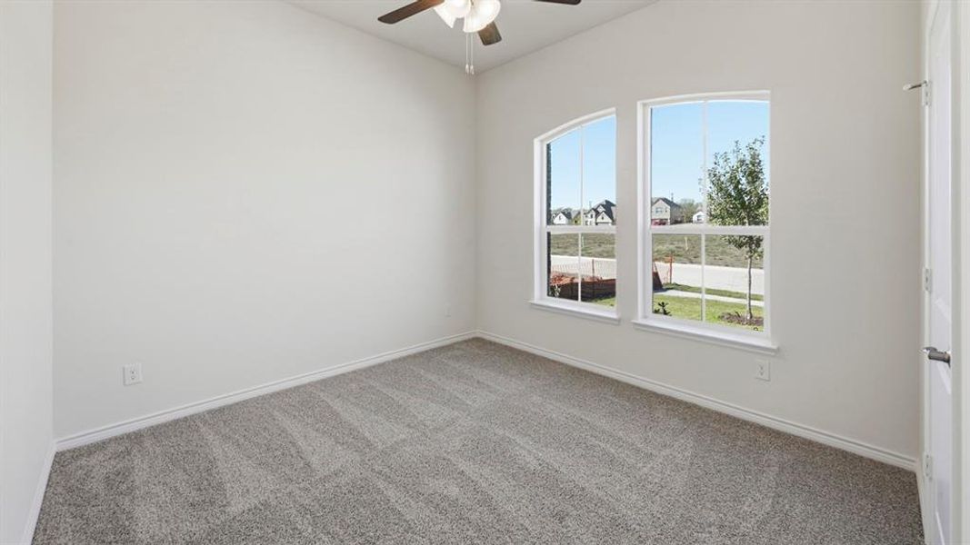Carpeted room featuring two arched windows, a ceiling fan with integrated lighting, and a white paneled door