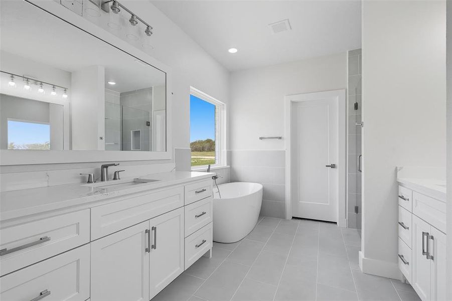 Full bathroom featuring a shower stall, vanity, a freestanding bath, light tile patterned flooring, and tile walls Full bathroom featuring a shower stall, vanity, a freestanding bath, light tile patterned flooring, and tile walls