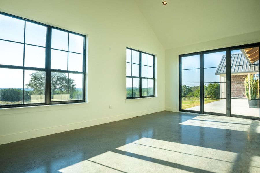 Spare room featuring concrete flooring and vaulted ceiling