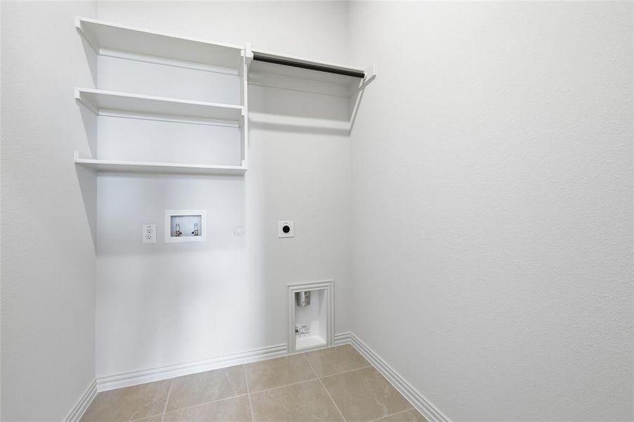 Laundry area with electric dryer hookup, washer hookup, hookup for a gas dryer, and light tile patterned flooring