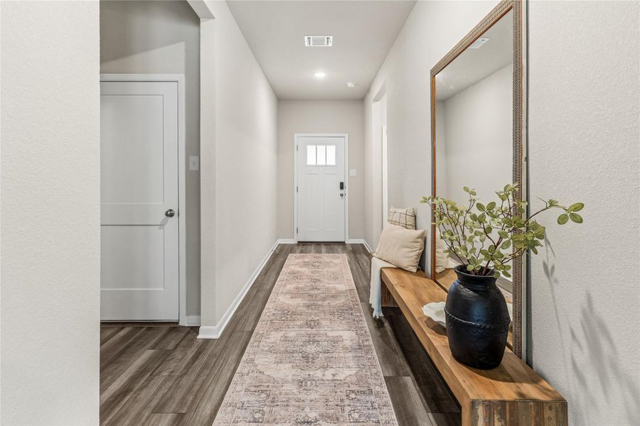 Enter into a bright hallway, featuring durable hardwood flooring and subtle recessed lighting leading to a charming front door. Enter into a bright hallway, featuring durable hardwood flooring and subtle recessed lighting leading to a charming front door.