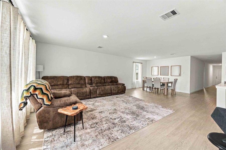 Spacious living and dining area with abundant natural light, featuring a large sectional sofa and a stylish dining set, perfect for entertaining.
