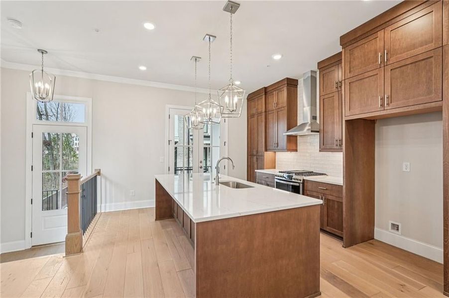 Kitchen featuring wood finish cabinets, suspended lighting, decorative backsplash, and ornamental molding