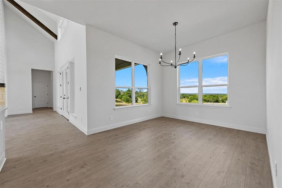 Unfurnished dining area with high vaulted ceiling, an inviting chandelier, and hardwood / wood-style flooring