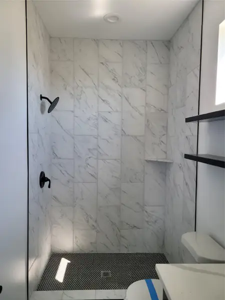Bathroom featuring a marble finish shower and vanity