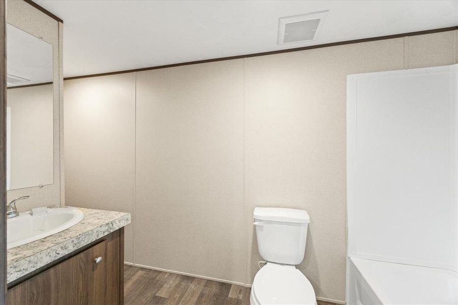 Bathroom vanity with an oval basin sink, patterned countertop, and wood-finish cabinetry