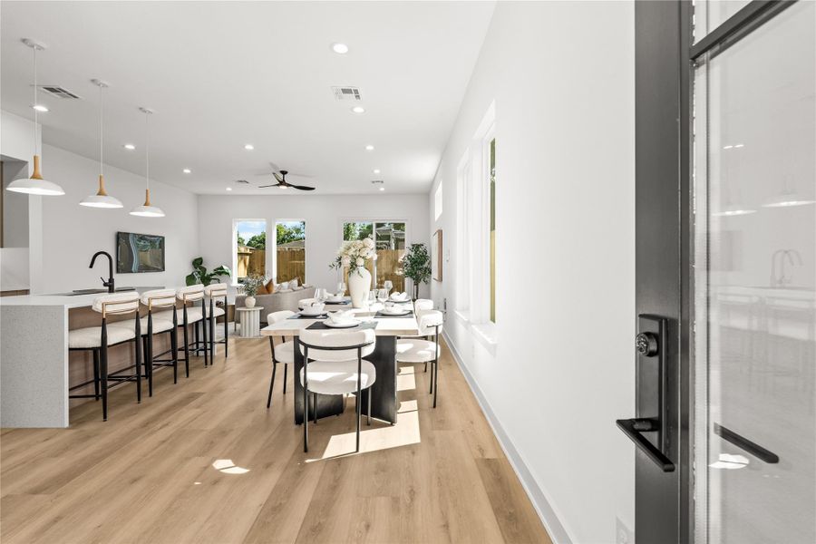 Inside, the open layout immediately feels spacious and bright, with light oak flooring connecting the living and dining areas. The kitchen features a large island with a white quartz waterfall countertop, making it a natural setup for quick meals or casual hanging out.