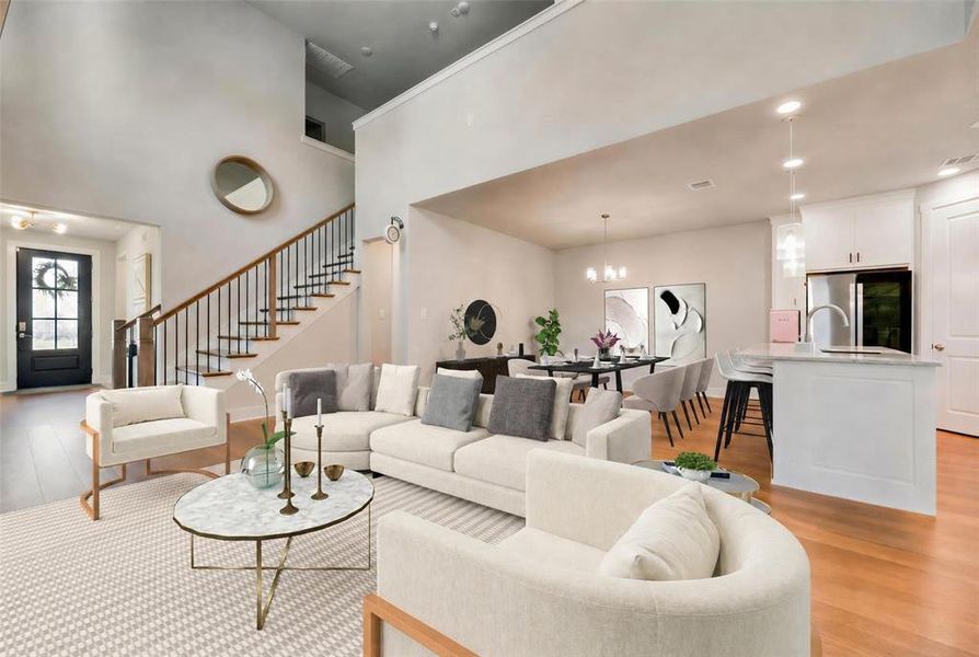 Open-concept living area featuring high ceilings, wood-finish flooring, and a contemporary staircase with iron balusters