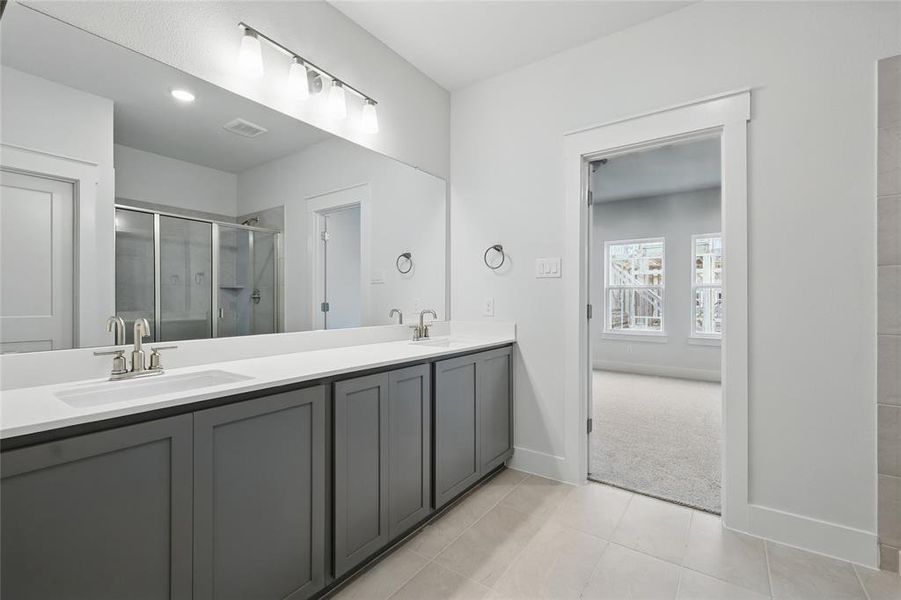 Full bathroom with double vanity, a shower stall, and light tile patterned flooring