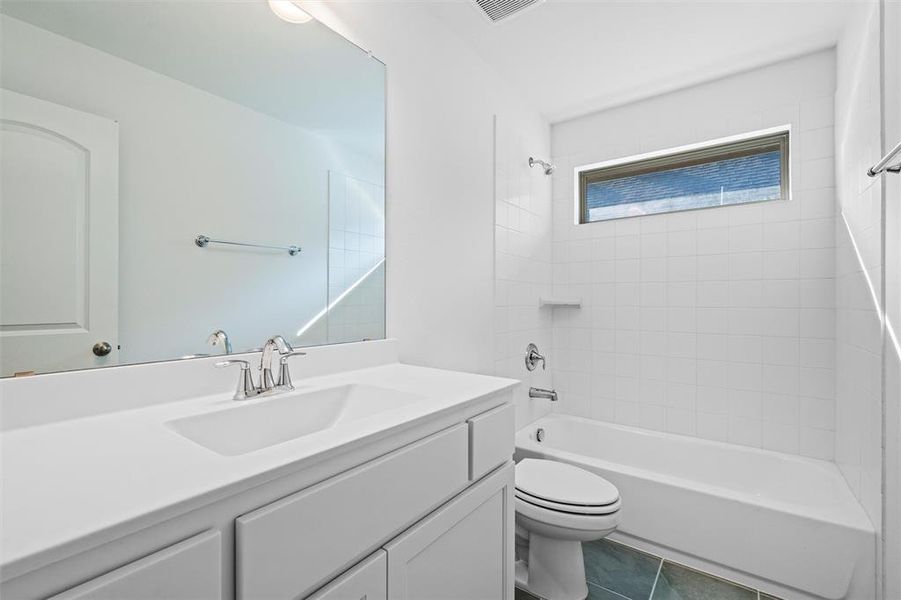 Full bathroom featuring toilet, tiled shower / bath, vanity, and tile patterned floors