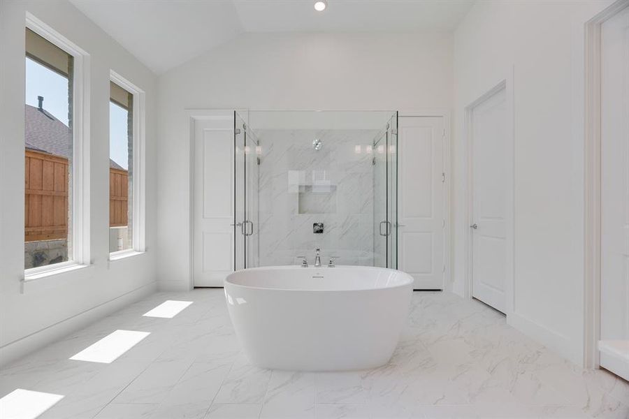 Bathroom with a marble finish shower, a freestanding bath, light marble finish flooring, lofted ceiling, and recessed lighting
