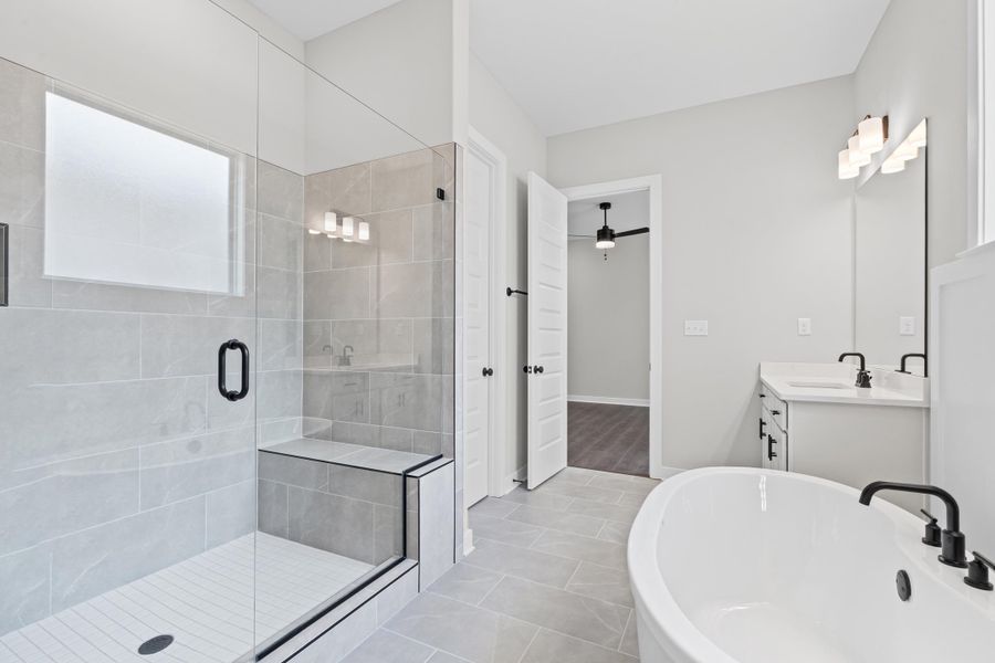 Bathroom featuring vanity, a stall shower, a soaking tub, and light tile patterned floors Bathroom featuring vanity, a stall shower, a soaking tub, and light tile patterned floors