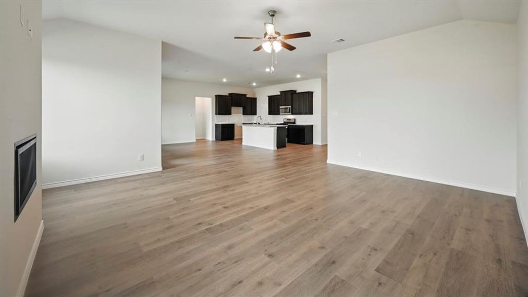 Unfurnished living room featuring light wood finished floors, a ceiling fan, and lofted ceiling